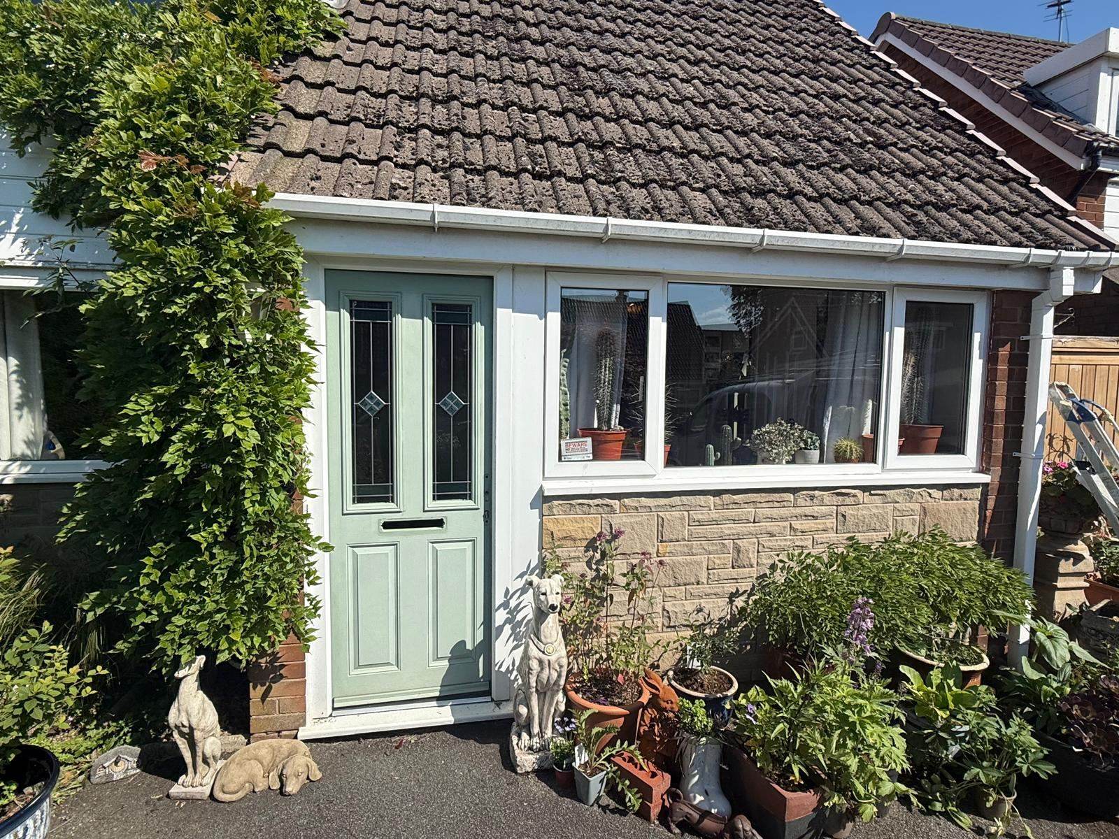 Stone cottage with front door sprayed sage green