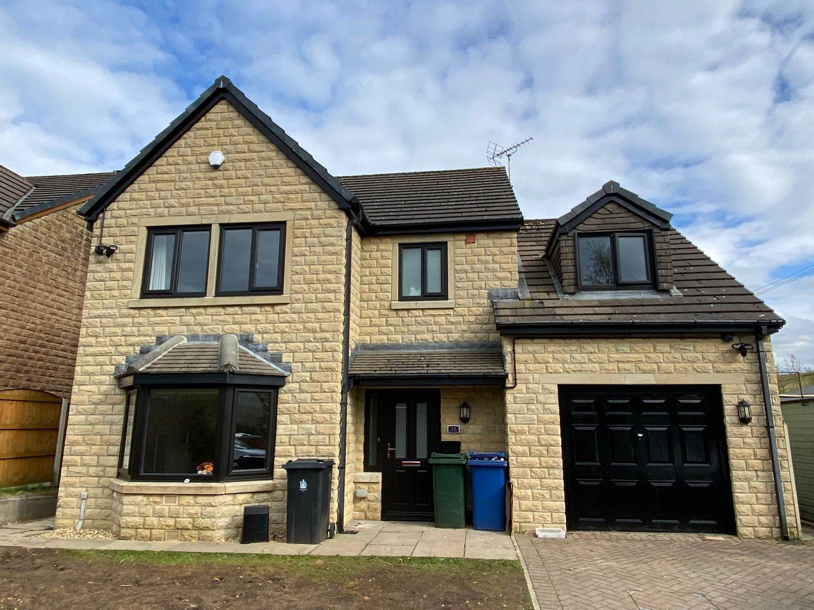 Stone detached house with black frames and black front door