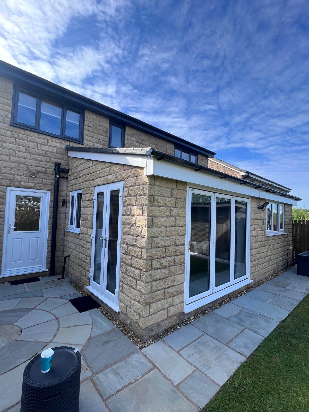 Stone rear extension with white bifold doors and anthracite windows above