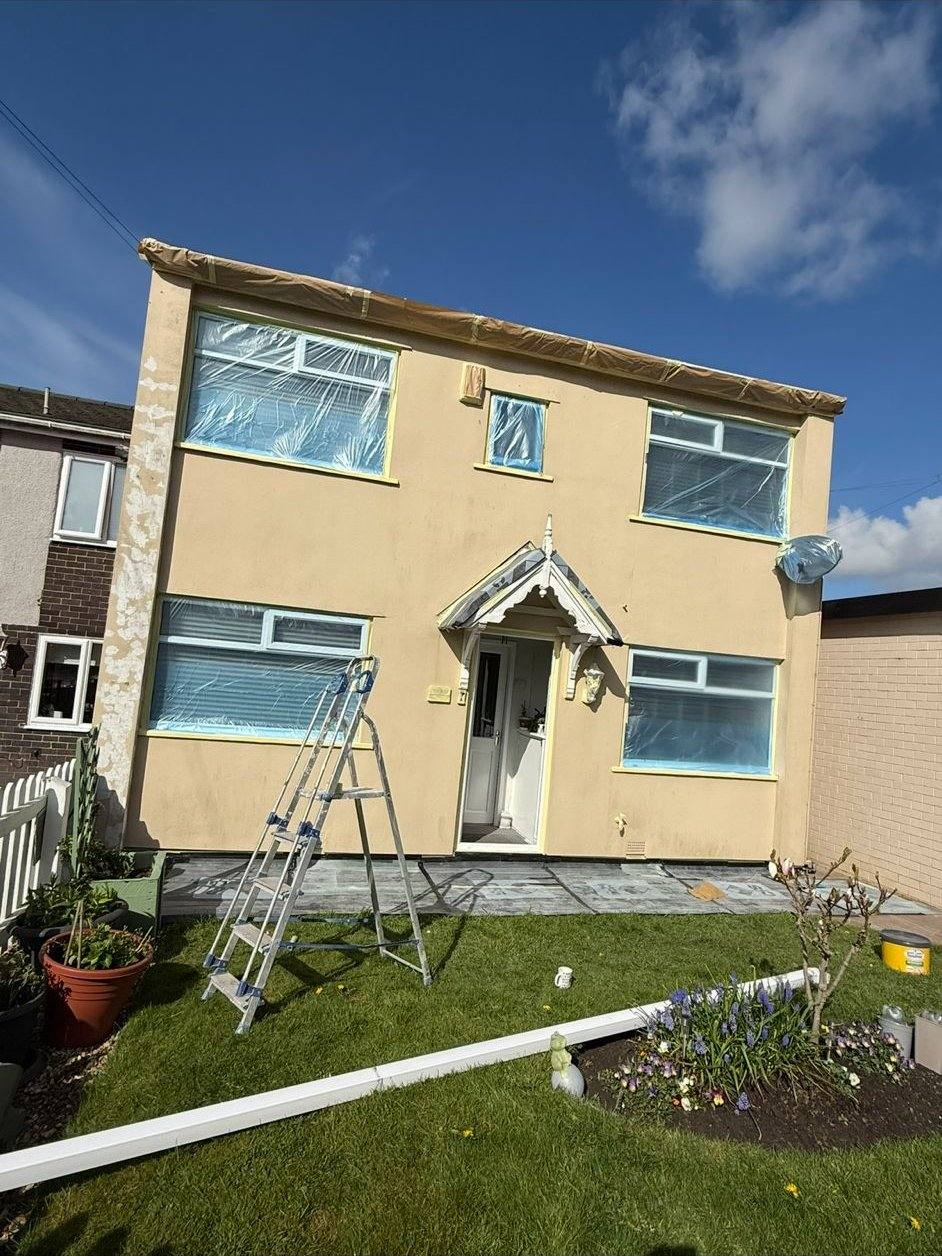 Semi-detached house with dirty tan render, masked up ready for spraying