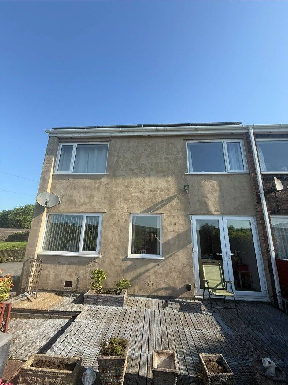 Rear elevation of a house with dirty beige render