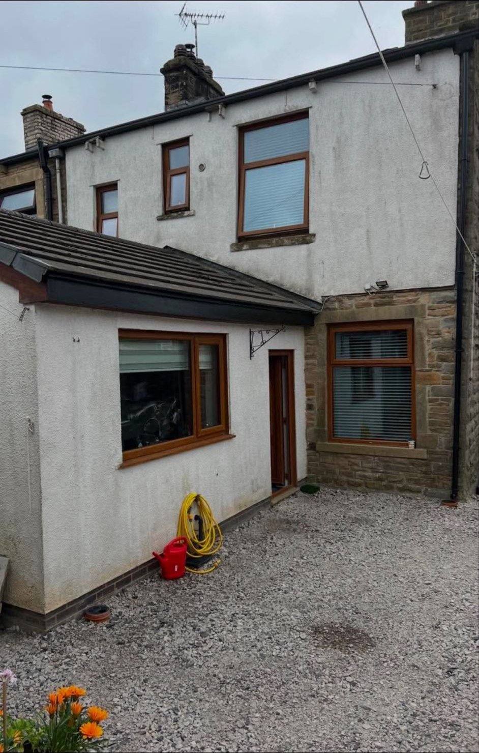 Stone house extension with dirty grey render